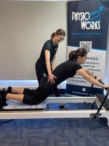 Person performing reformer Pilates exercise on a Pilates reformer machine.