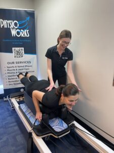 Physiotherapist guiding a patient through a reformer Pilates session.