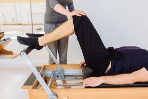 Person practising Reformer Pilates with a physiotherapist at PhysioWorks.