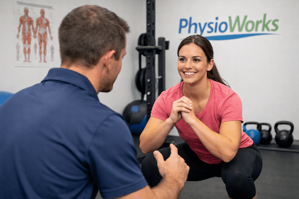 Physiotherapist guiding a closed kinetic chain squat exercise