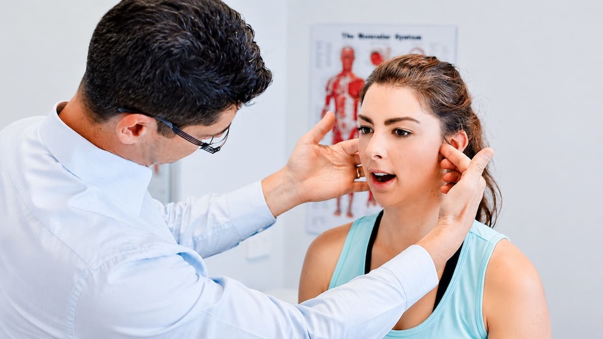 Physiotherapist assessing jaw movement during a TMJ examination