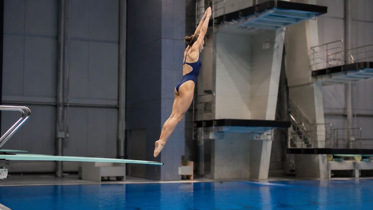 Competitive diver performing a controlled springboard take-off above an indoor diving pool