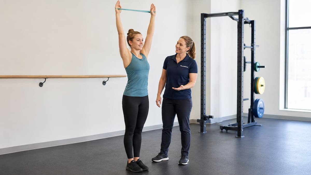 Physiotherapist supervising overhead shoulder and trunk control rehabilitation for competitive diving